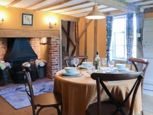 a dining room with a table and a fireplace at Bell Corner Cottage in Cratfield