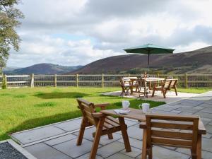 a patio with a table and chairs and an umbrella at Gorsddu in Llanwrthwl