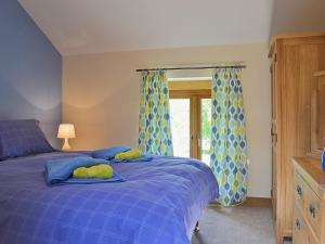 a bedroom with a blue bed with blue and yellow curtains at Gorsddu in Llanwrthwl