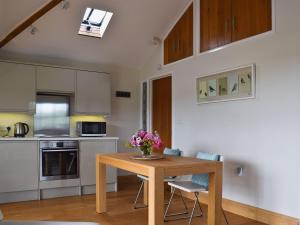 una cocina con una mesa de madera con flores. en Hurdlemakers Loft, en Upper Brailes