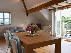 uma mesa de jantar com um vaso de flores em Hurdlemakers Loft em Upper Brailes