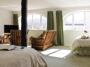 a bedroom with two chairs and a bed and windows at Dairy Cottage in Barnstaple