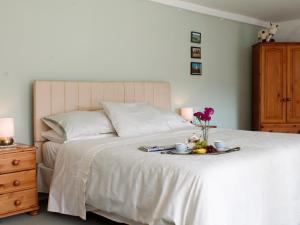 a bedroom with a bed with a tray of food on it at Dairy Cottage in Barnstaple