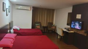 een hotelkamer met een rood bed en een flatscreen-tv bij d arissa house in Kota Bharu