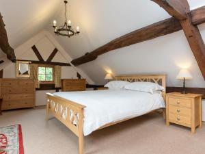 a bedroom with a large white bed and wooden furniture at Brook House in Mathon