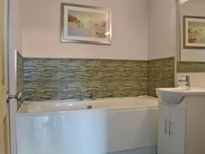 a bathroom with a bath tub and a sink at The Old Classroom in Saint Neot