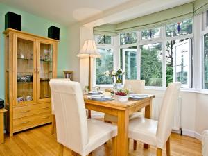 a dining room with a wooden table and white chairs at Oldway Apartment in Paignton