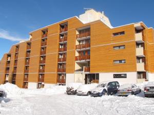 a large building with cars parked in the snow at Studio cabine cosy avec balcon, au pied des pistes et des commerces. - FR-1-340-267 in Chamrousse