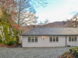 a white house with a gravel driveway at The Coach House in Grasmere