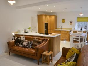 a living room with a couch and a kitchen at The Coach House in Grasmere