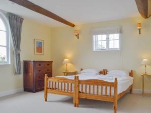 um quarto com uma cama de madeira e 2 janelas em Cronkhill Farmhouse em Wroxeter
