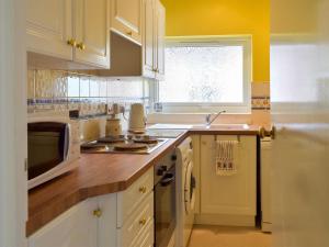 a kitchen with white cabinets and a microwave at Felix Court in Felixstowe