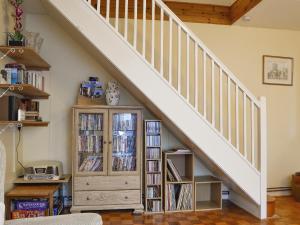 een woonkamer met een trap en een boekenplank met dvd's bij Draigs Cottage in Abergavenny