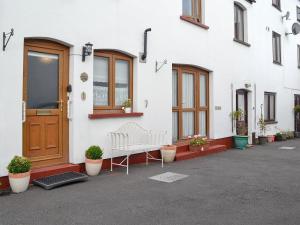 a white building with a bench in front of it at Draigs Cottage in Abergavenny