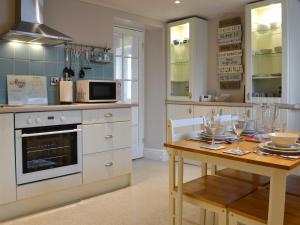 a kitchen with a table and a stove and microwave at The Cottage in Penrhos-Lligwy