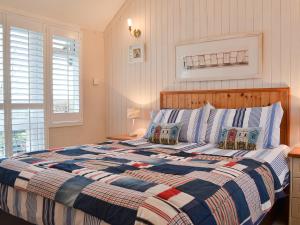a bedroom with a bed with a blue and white quilt at The Cottage in Penrhos-Lligwy