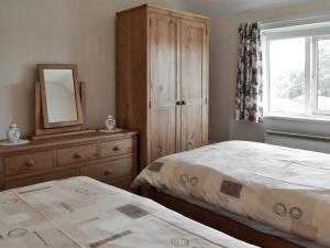 a bedroom with two beds and a dresser and a mirror at Eventide in Biggleswade