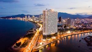 Una ciudad de noche con un edificio alto y el agua en Muong Thanh Luxury Khanh Hoa, en Nha Trang