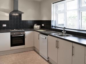 a kitchen with white cabinets and a sink and a window at Eventide in Biggleswade