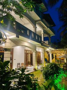 a large white building with a patio at night at Plantation Surf Inn & Restaurant in Midigama