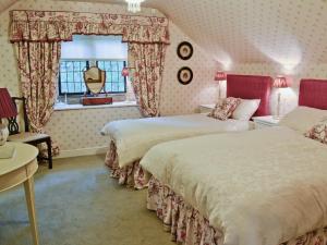 The Coach House في Great Easton: غرفة نوم بسريرين ونافذة