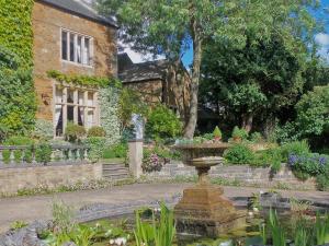 a garden with a fountain in front of a house at The Coach House in Great Easton