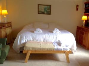 a bedroom with a bed with white sheets and a bench at Gardeners Delight Studio La Casita Barrio Chapelco in San Martín de los Andes