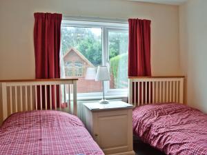 a bedroom with two beds and a window with red curtains at Burnbank in Kirkgunzeon