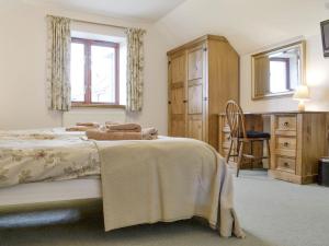 a bedroom with a bed and a desk and a chair at White Hill Farm Cottage in Dingestow