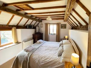 ein Schlafzimmer mit einem großen Bett in einem Zimmer mit Holzdecken in der Unterkunft Titchbourne Cottage in Clee Saint Margaret