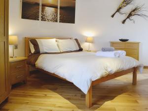 um quarto com uma cama grande e lençóis brancos em The Windmill em Coedana