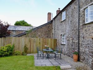 a patio with a table and chairs next to a building at Barton Cottage in North Petherwin