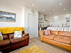 a living room with two leather couches and a kitchen at Below Decks in Turnchapel