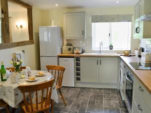 een keuken met een tafel en een witte koelkast bij Acorn Cottage - Ukc1812 in South Perrott
