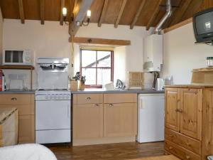 a kitchen with a white stove top oven next to a window at The Byre in Morland