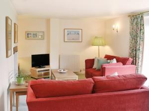 uma sala de estar com dois sofás vermelhos e uma televisão em The Linhay em East Worlington