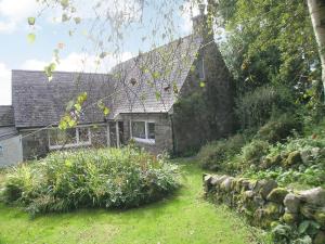 Holly Cottage - 28140 في Boreland of Colvend: منزل حجري قديم وامامه حديقة