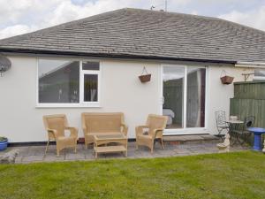 eine Terrasse mit Stühlen und einem Tisch vor einem Haus in der Unterkunft Rossall Beach Cottage in Cleveleys