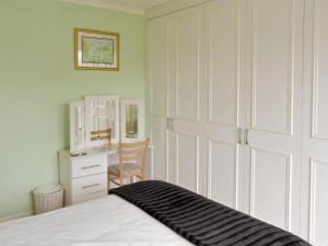 a bedroom with a bed and a dresser and a mirror at Rossall Beach Cottage in Cleveleys