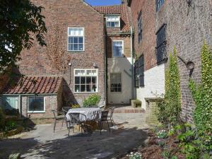 a patio with a table and chairs in front of a brick building at Nells Cottage in Bridlington