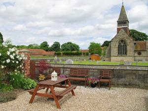 a picnic table and benches in front of a church at The Old Forge in West Lutton