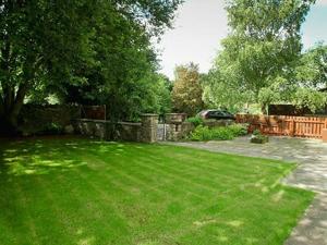 a yard with a fence and a green lawn at Brewers Cottage in Cropton