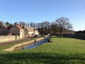 a river in a village with a green field at Jug And Glass Cottage in Upper Langwith