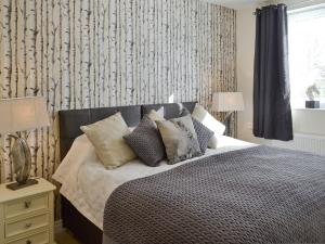 a bedroom with a bed with pillows on it at Willow Tree Cottage in Foxholes