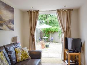 a living room with a couch and a television at Field View Cottage in Bruisyard