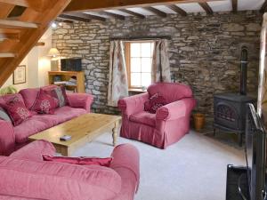 a living room with two couches and a wood stove at The Corn Mill in Branthwaite