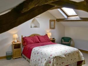 a bedroom with a bed with red sheets and a window at The Corn Mill in Branthwaite