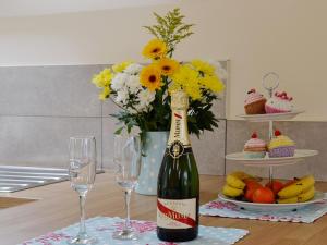 Horrabridge的住宿－喜鵲之巢度假屋，一瓶葡萄酒和两杯带鲜花的桌子