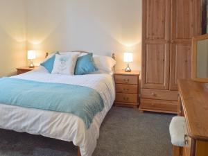 a bedroom with a bed with two night stands and two lamps at Glebe Cottage in Mautby