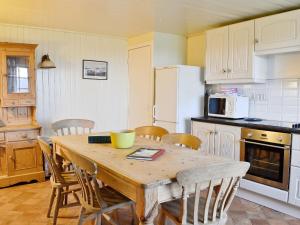uma cozinha com uma mesa de madeira e cadeiras numa cozinha em Buckhood - Swwy em Pearsie